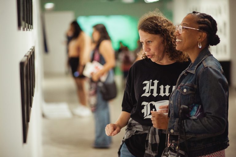 Gallery visitors look at artwork at Illinois' Humanities' 2019 Envisioning Justice Exhibition