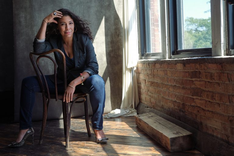 Portrait of Jasmin Cardenas sitting in a chair in a sun-lit studio space