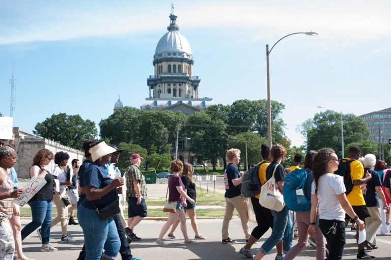 A crowd marches past the Illinois State Capitol building
